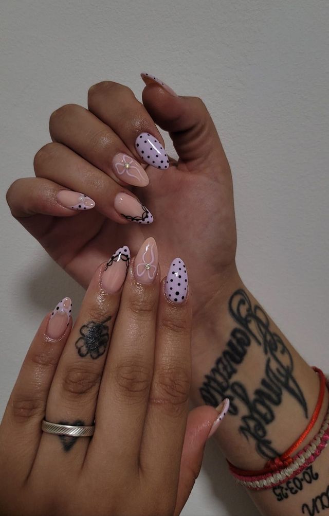 Uñas lila claro con lunares negros y mariposa en línea