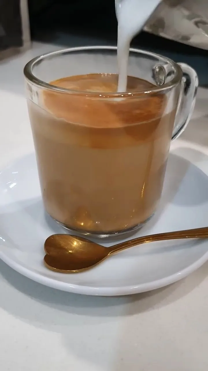 Café con leche servido en vaso de cristal