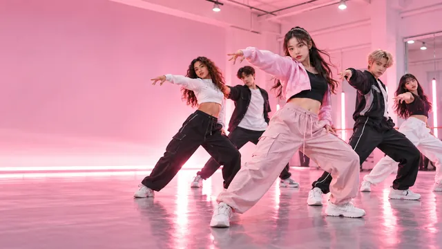Grupo de jóvenes bailando una coreografía de K-pop en un estudio rosado