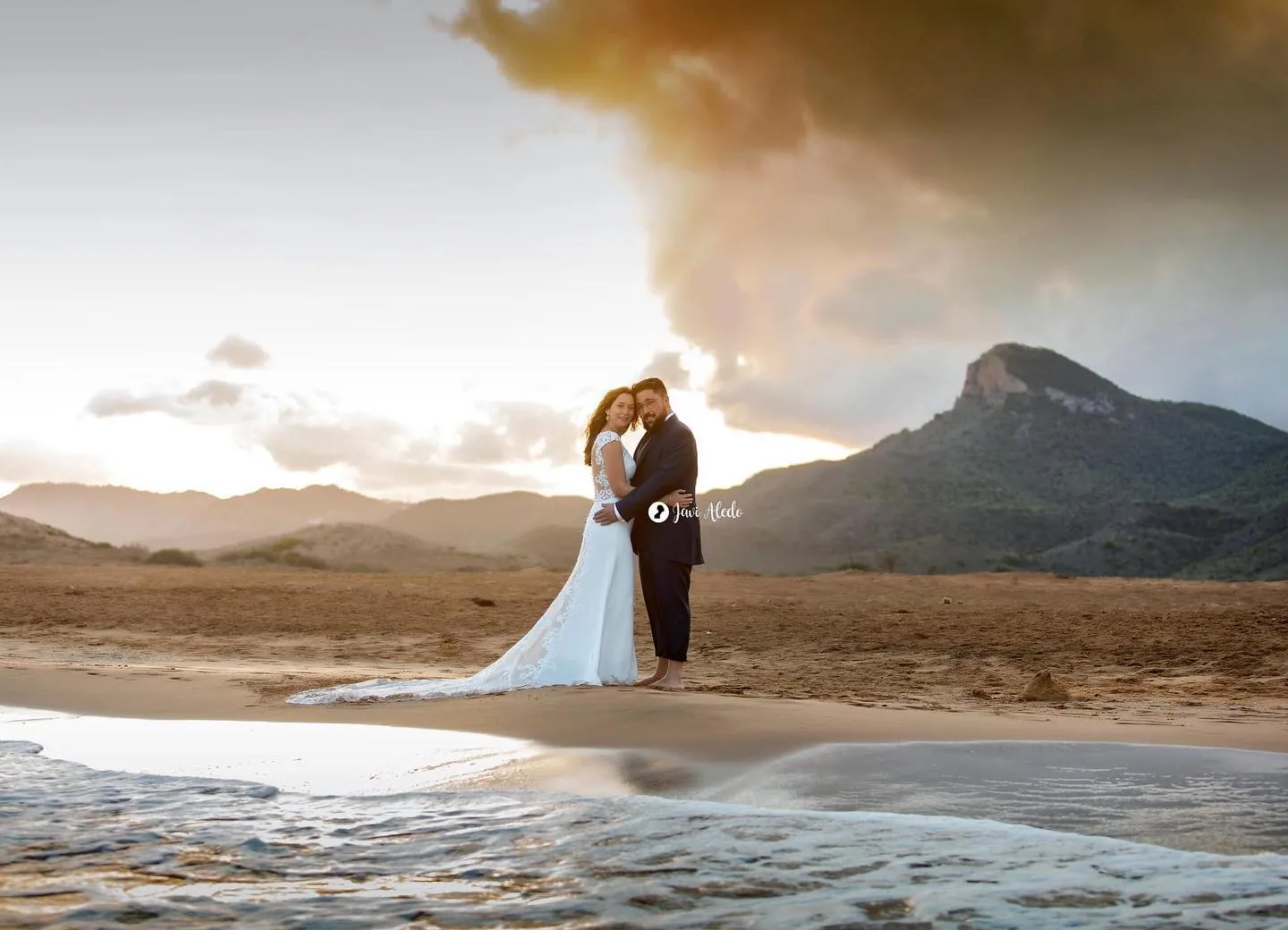 Novios abrazados en la orilla al atardecer