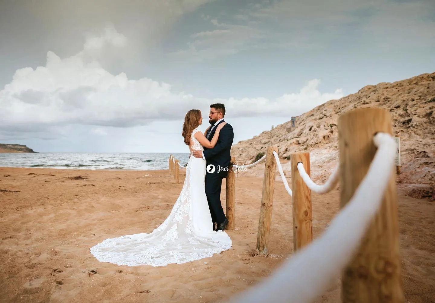 Novios en una playa con un poste de madera