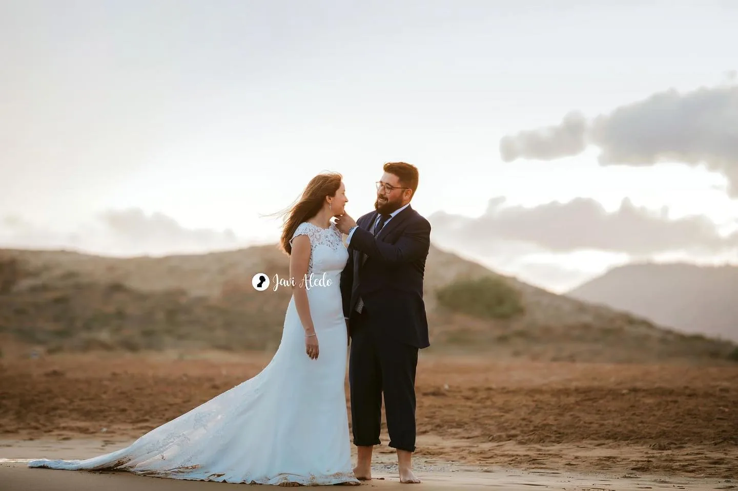 Novios caminando por una playa entre dunas