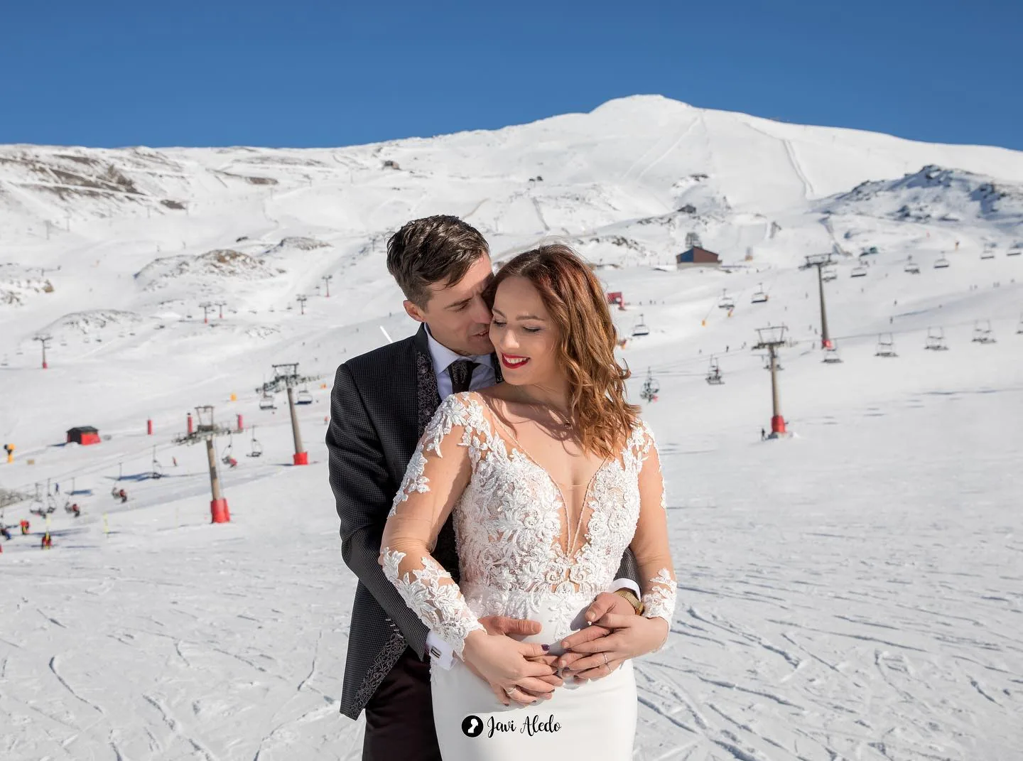 Novios abrazados con las pistas de Sierra Nevada al fondo