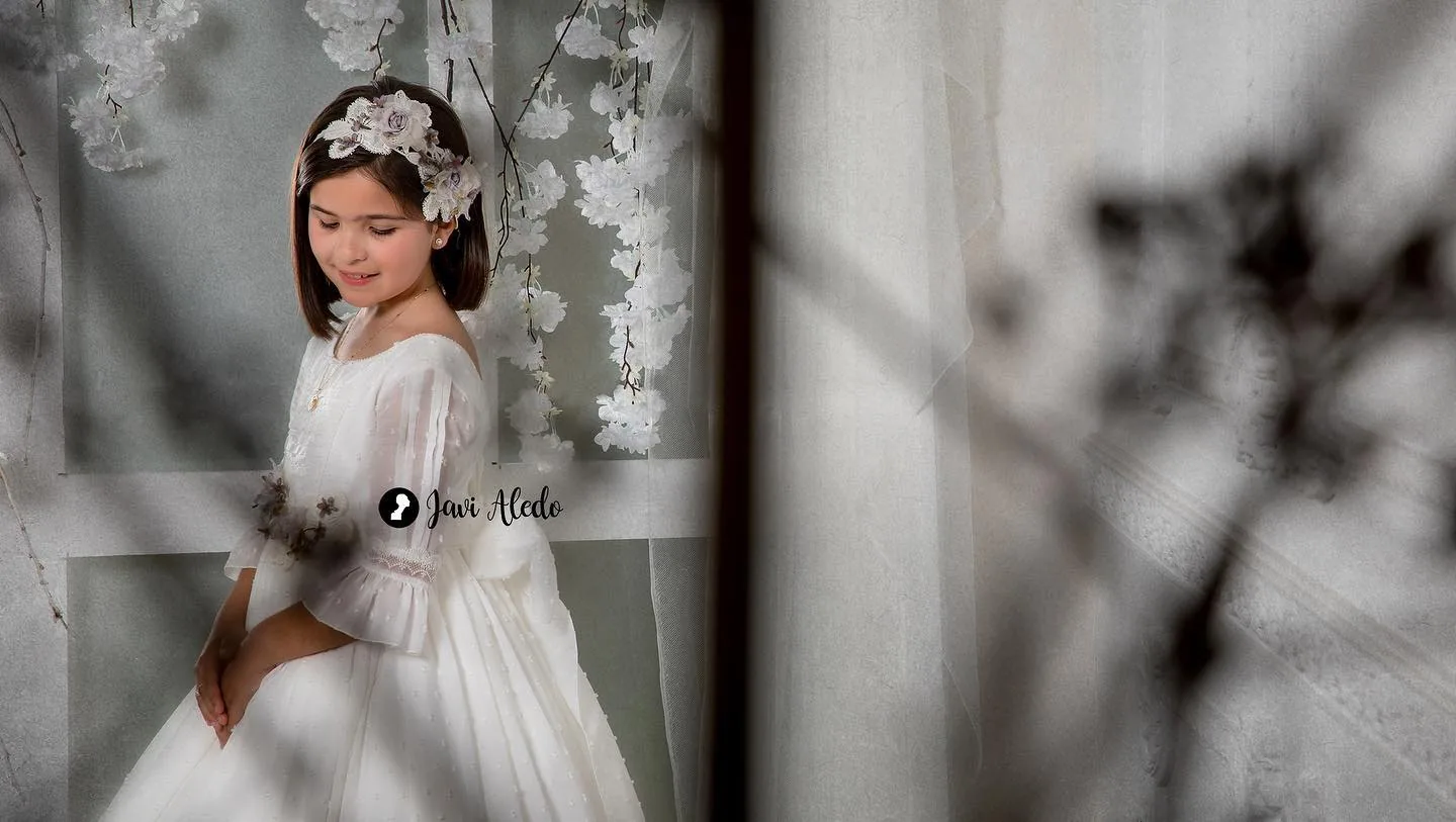 Niña de comunión entre flores blancas