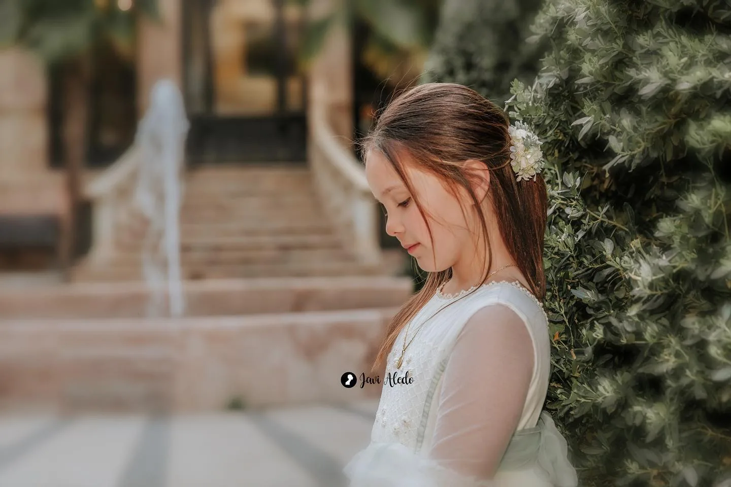 Niña de comunión de perfil en un jardín