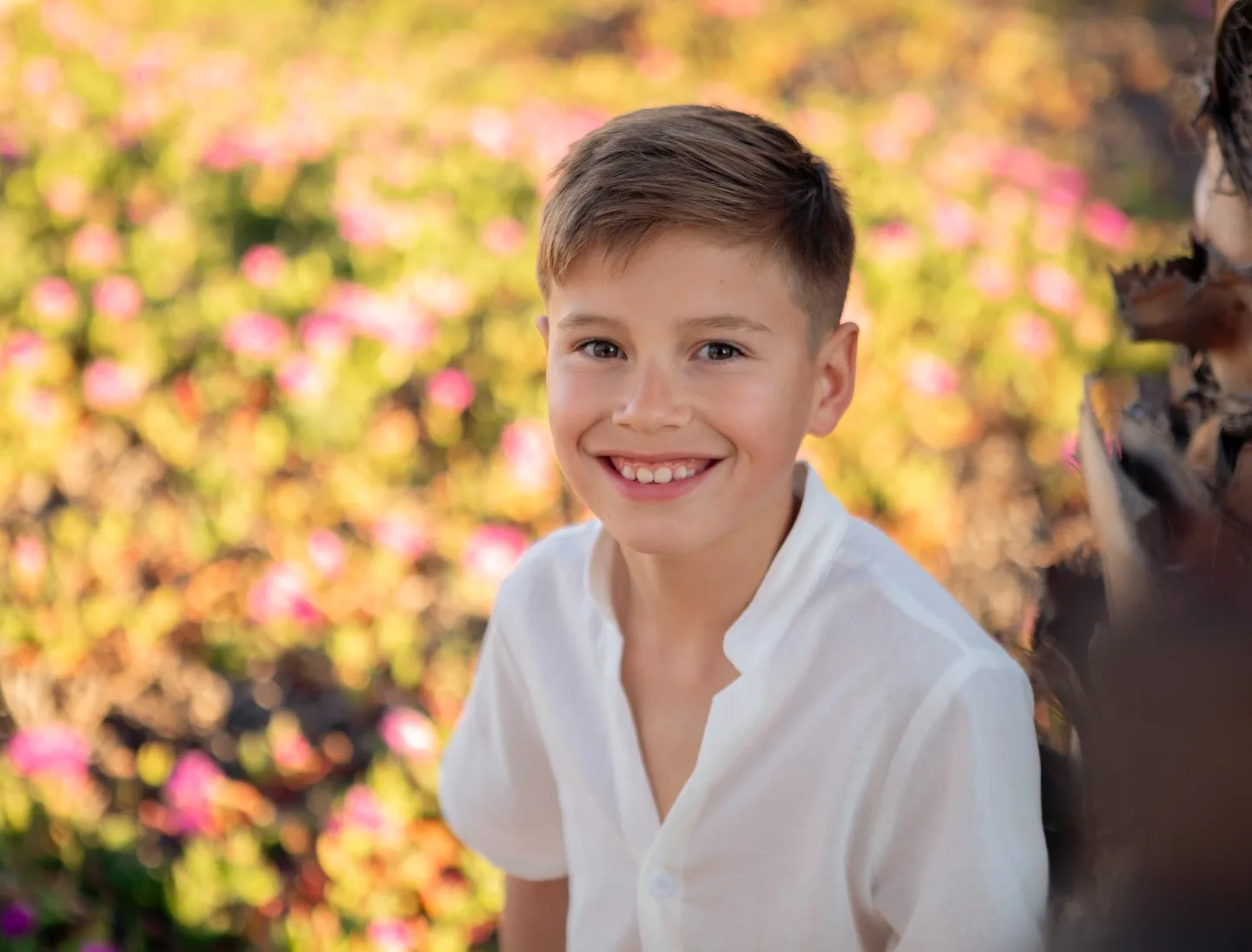 Niño de comunión sonriente entre flores al atardecer