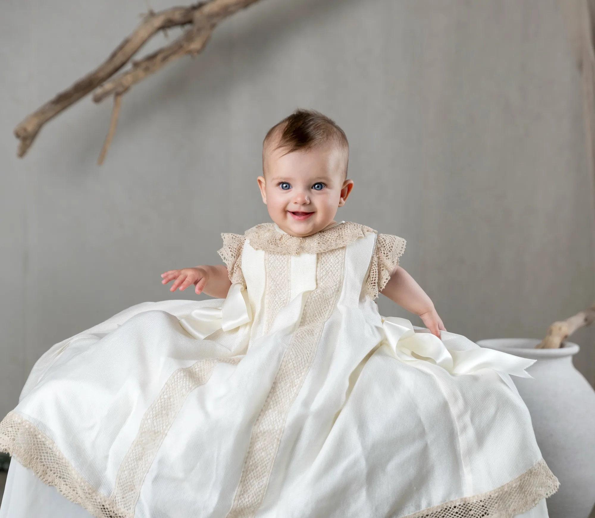 Bebé con traje de bautizo sentado en el estudio