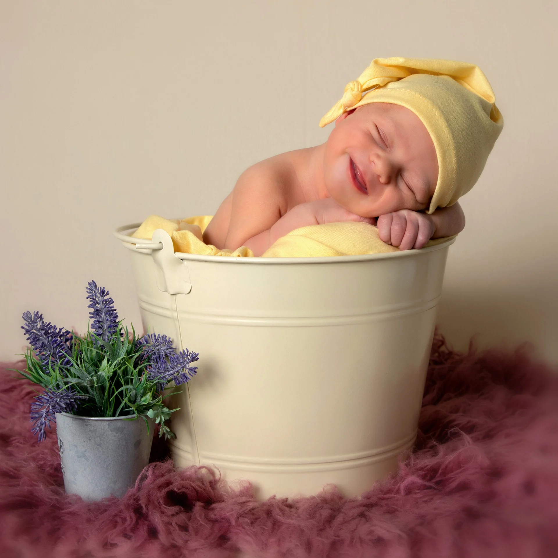 Recién nacido con gorro amarillo dentro de un cubo decorativo