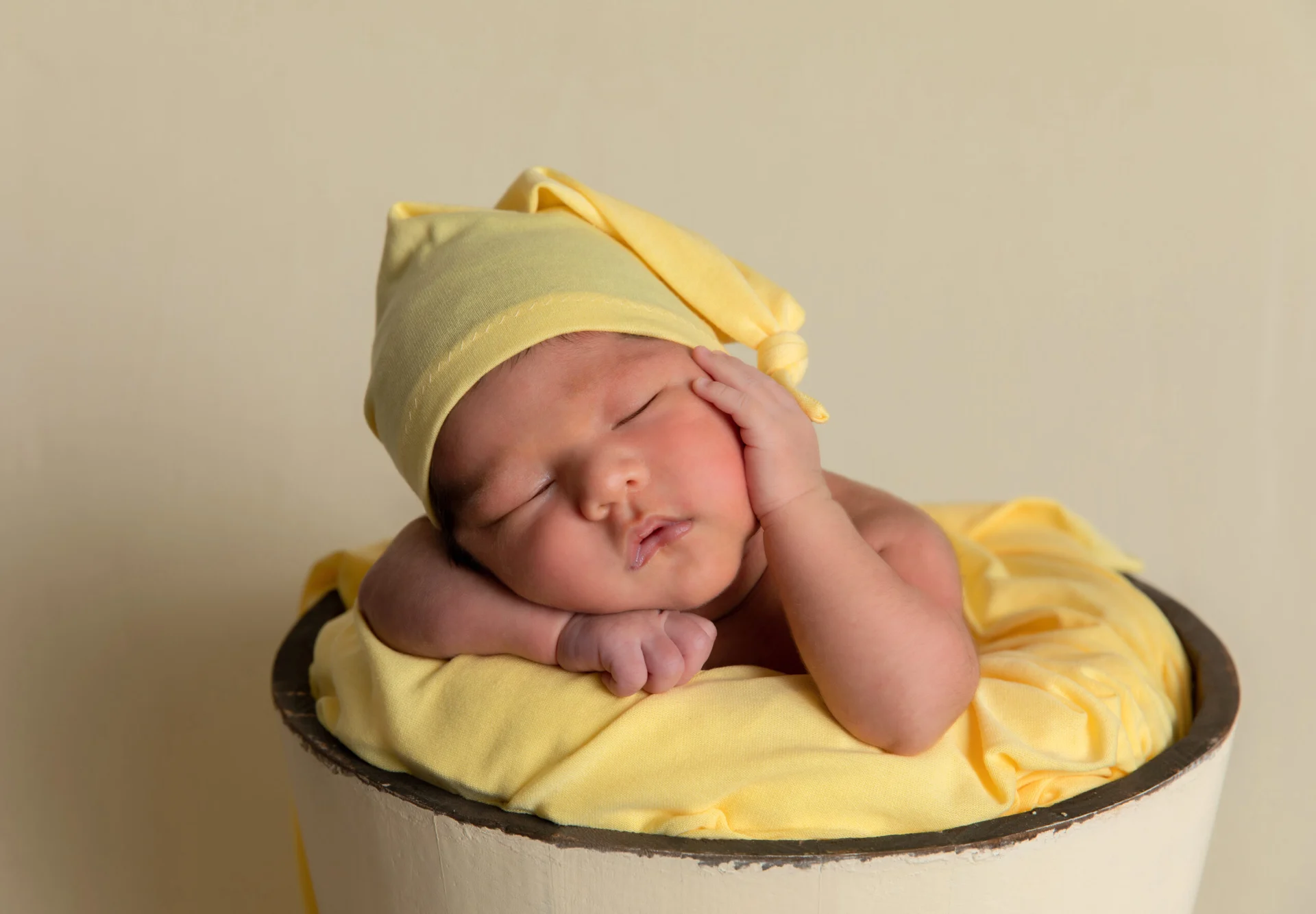 Recién nacido dormido en un cuenco amarillo
