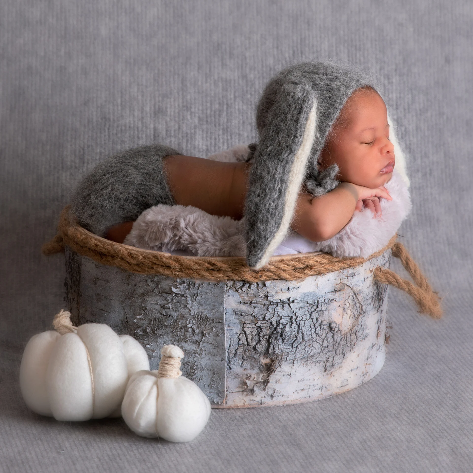 Recién nacido con gorro gris en un recipiente de madera