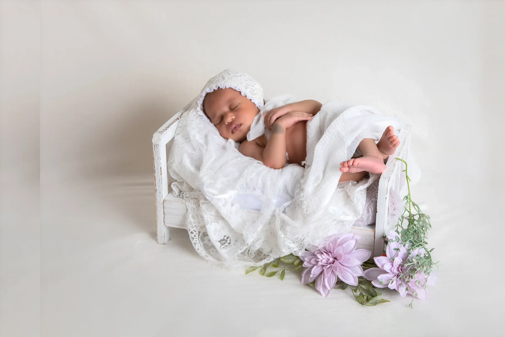 Recién nacido dormido entre flores blancas