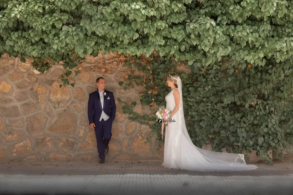 Novio esperando frente a un muro de hiedra