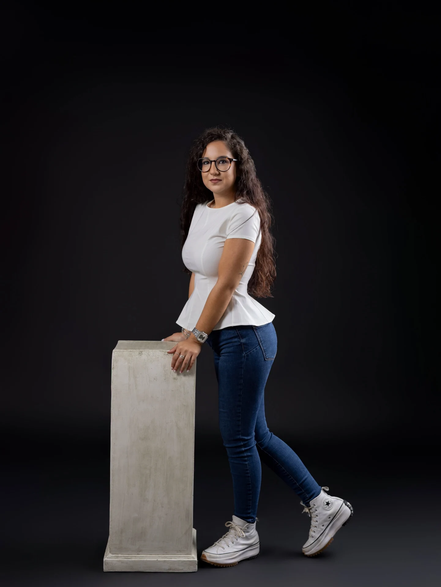 Joven apoyada en un pedestal en el estudio