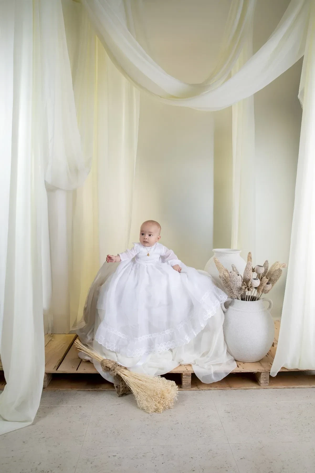 Bebé con vestido blanco en un decorado claro