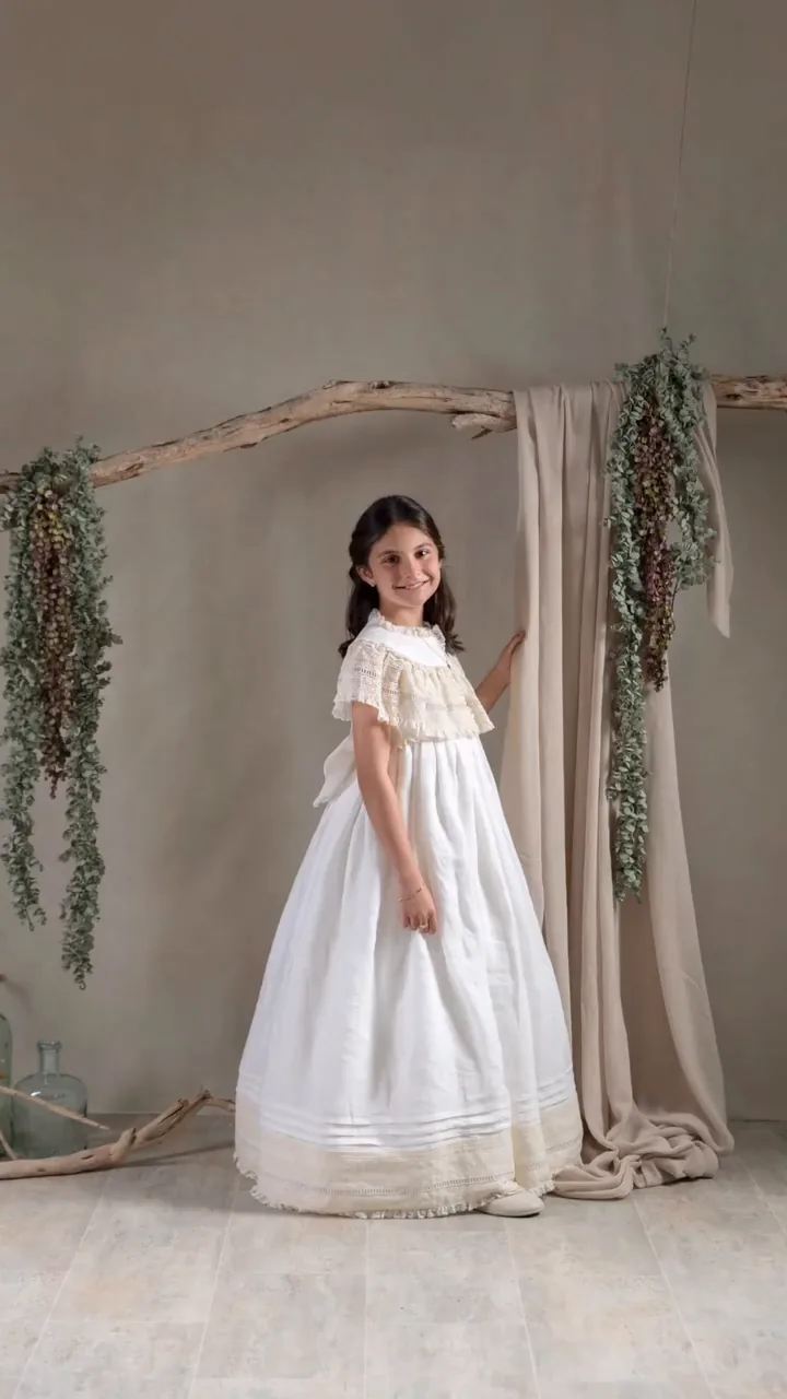 Niña de comunión con vestido largo en un decorado claro