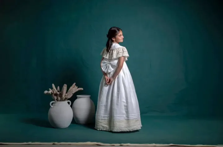 Niña de comunión de cuerpo entero sobre fondo verde