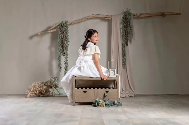 Niña de comunión sentada en un baúl