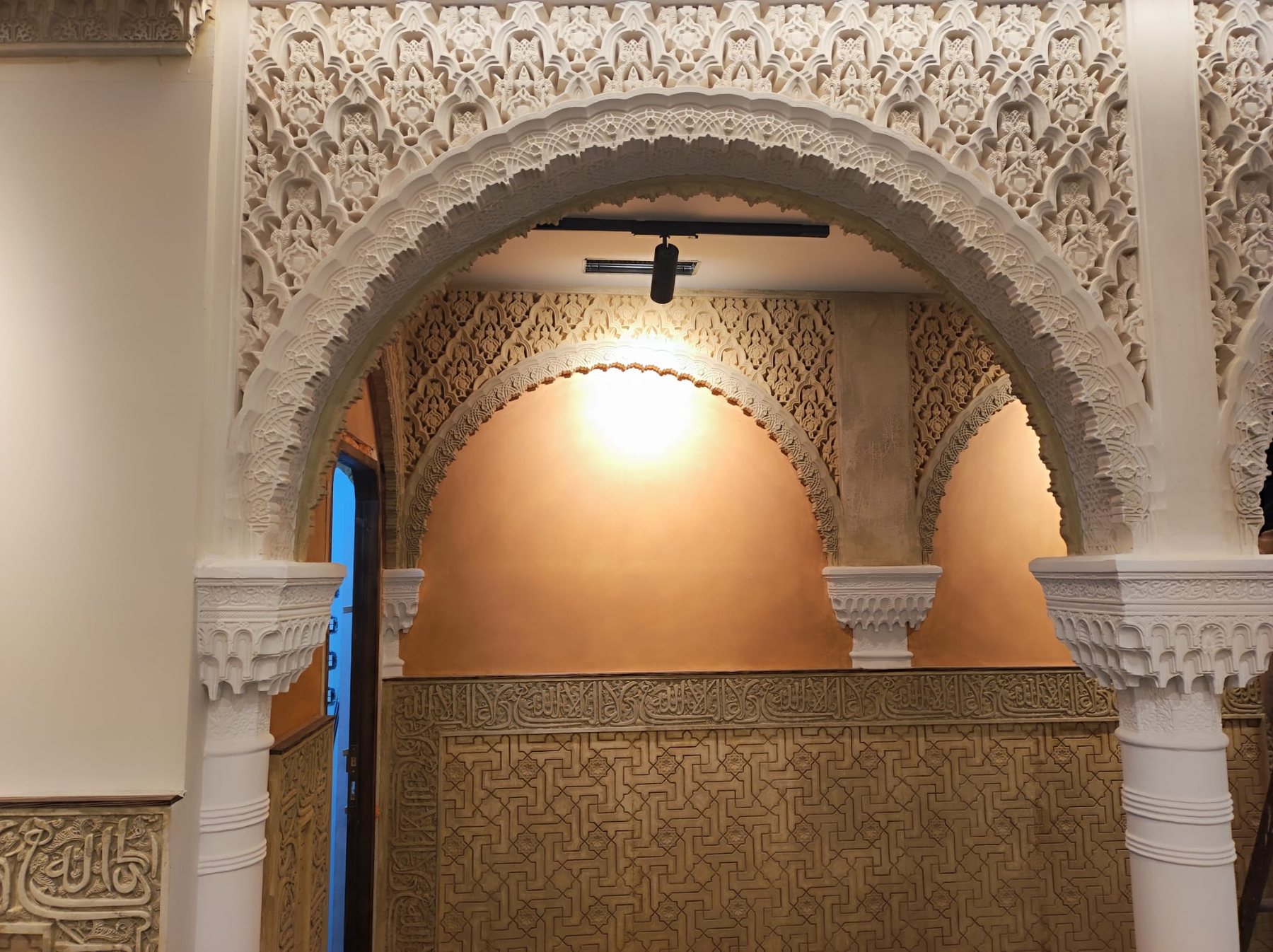 Arco nazarí de yesería iluminado en el interior de La Taranta